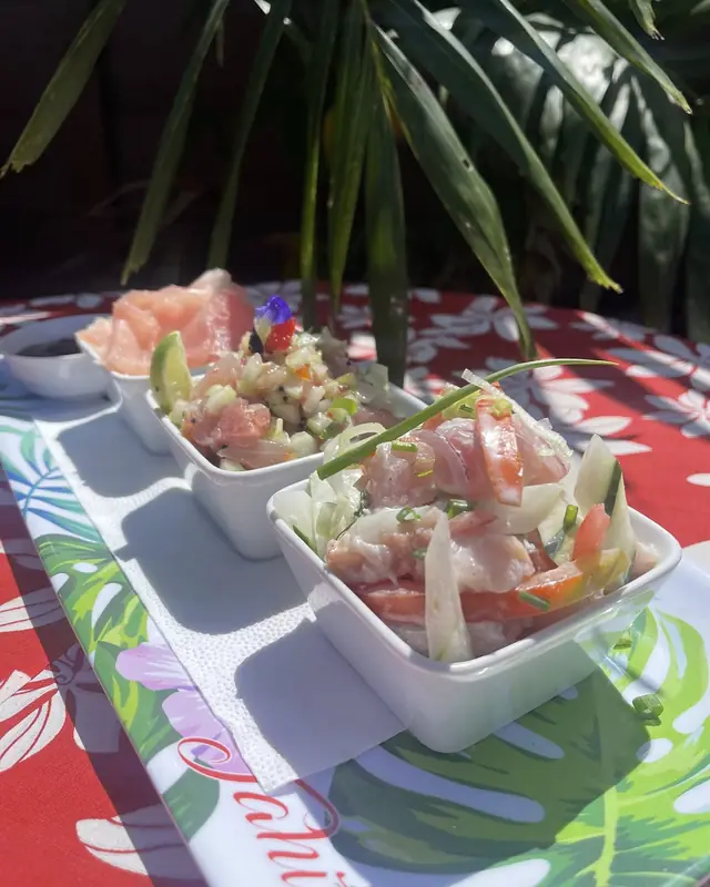 Trilogie de poisson servie en trois verrines, sur une nappe à fleurs de tiare